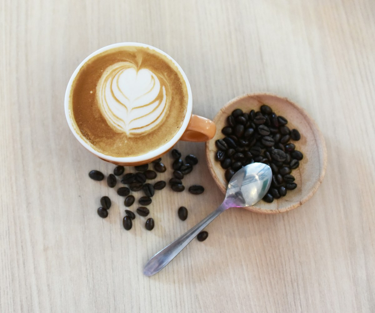 A creamy latte with heart-shaped foam and roasted beans in soft morning light